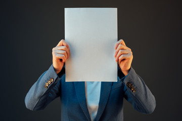 Businesswoman covering face with blank paper as copy space