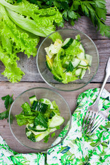 Green salad with cucumber in glass bowls, top view