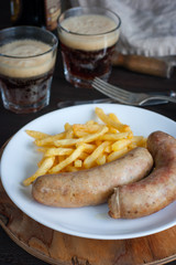Sausages and potatoes with dark beer on a wooden table, selective focus