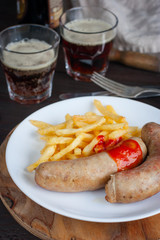 Sausages and potatoes with dark beer on a wooden table, selective focus
