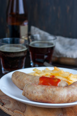 Sausages and potatoes with dark beer on a wooden table, selective focus