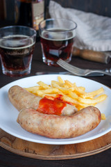 Sausages and potatoes with dark beer on a wooden table, selective focus