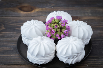White airy Zephyr lies on the plate against a dark wooden table