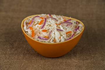 Sauerkraut in bowl on brown background
