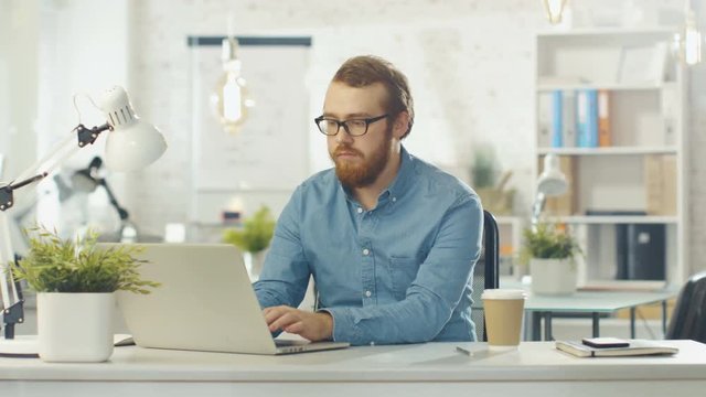  Focused Young Tech Guy Interrupts Typing on His Laptop, Folds His Hands and Looks DIrectly Into The Camera.Shot on RED Cinema Camera in 4K (UHD).