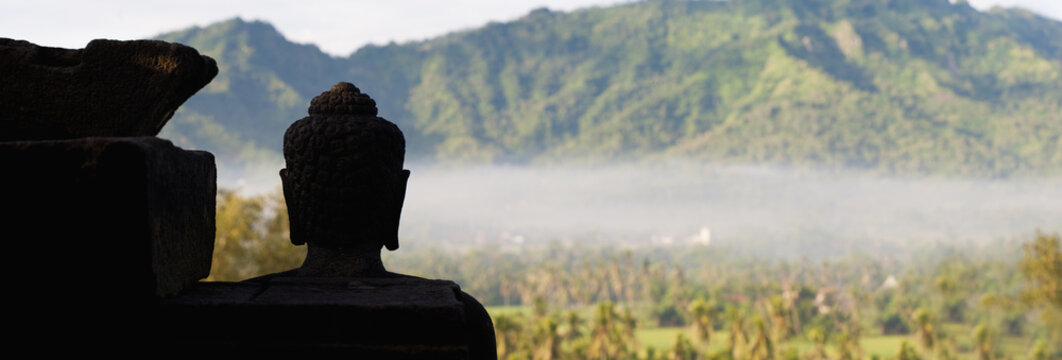 Silhouetted Buddha at Borobudur Temple at sunrise, Java, Indonesia