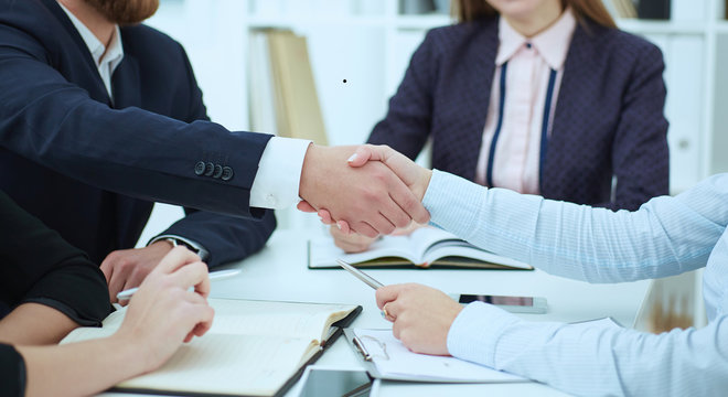 Male and female handshake in office. Serious business and partnership concept. Partners made deal, sealed with handclasp.