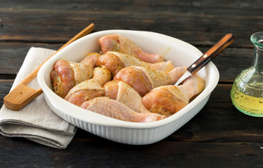 Chicken legs ready for baking on the dark wooden table