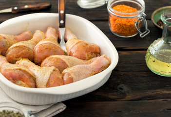 Marinated chicken legs ready for baking on the wooden table