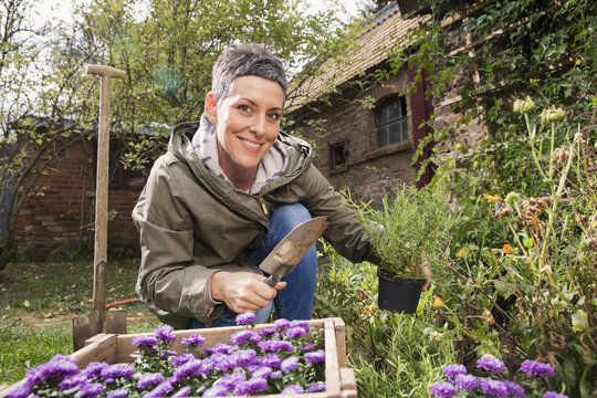 Portrait of happy woman gardening in back yard