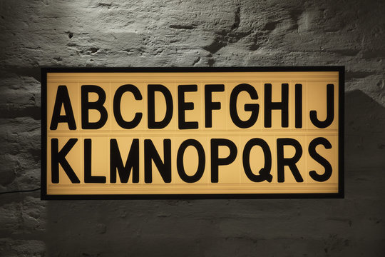 Close-up of Alphabets signboard against gray wall