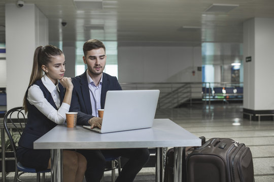 Young business couple using laptop at table in airport