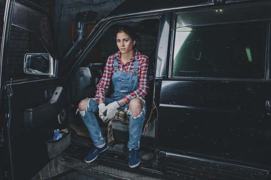 Portrait of confident female mechanic sitting in car at workshop