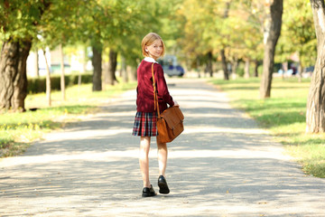Schoolgirl walking along alley in green park