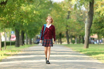 Schoolgirl walking along alley in green park