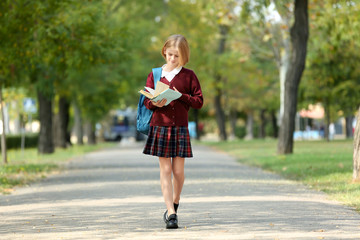 Fototapeta premium Schoolgirl walking along alley in green park