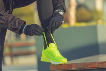 Urban jogger tying running shoes in the park.
