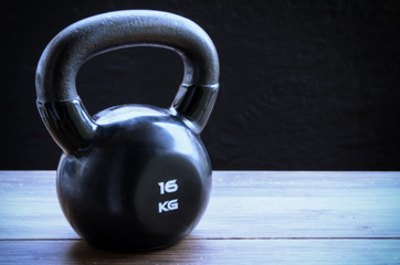 Naklejka na ściany i meble Black kettlebell on wooden background with copyspace. Concept for sport and gym.