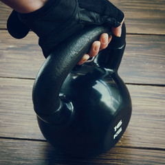 Naklejka na ściany i meble Close up of black kettlebell and sport gloves on dark background. Concept for gym and fitness.