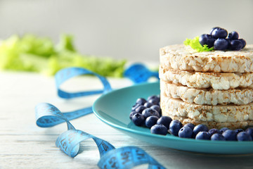 Round rice crispbreads with blueberries and measuring tape on table, closeup