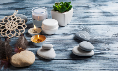 Spa background with cosmetics bottles, stones and lit candles