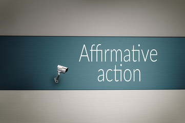Affirmative action text on the wall with surveillance camera.