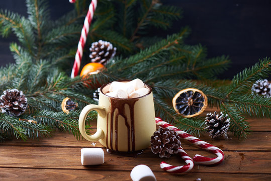mug with hot chocolate with dripping chocolate, christmas tree, tangerines, peppermint stick and marshmallow on a wooden background. Dark photo. Empty space for text. Toned for art effect