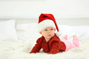 Cute baby in Santa hat on bed