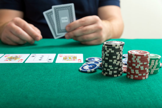 chips and cards for poker in hand on green table