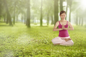 Asian female doing yoga outdoor on a green grass