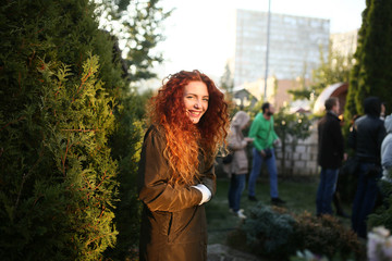 beautiful young woman with red curly hair standing outdoors and