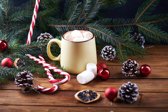 mug with hot chocolate, christmas tree, tangerines, peppermint stick and marshmallow on a wooden background. Dark photo. Empty space for text