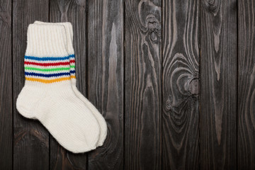 Obraz na płótnie Canvas Knit white wool socks on dark wooden background.