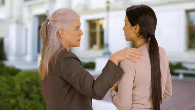 A professor advises a student on campus. A student talk to a professor at university. 