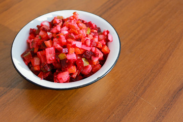 Russian beet salad vinaigrette in rustic bowl on wooden table