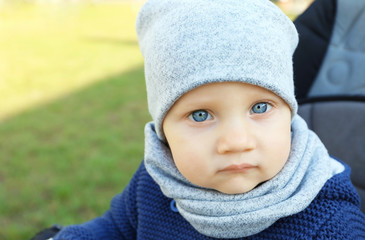 Cute little baby sitting in stroller outdoors, close up view