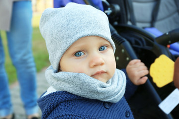 Cute little baby near stroller outdoors, close up view