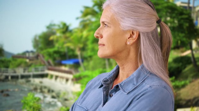 An older woman takes in the sights in the tropics. A side-view of an elderly woman on vacation. 