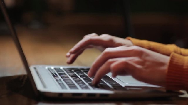 Moving shot of a woman's hands working on a laptop.