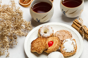 Galletas sabrosas junto a dos tazas de té sobre un fondo blanco. Vista superior y de cerca