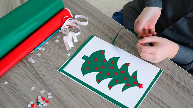 Teen Boy making Christmas card from colored self-adhesive papers