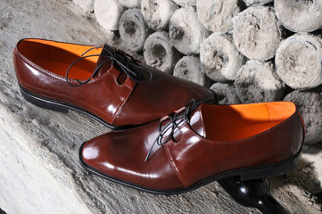 Classic shiny brown mens shoes, standing on interesting background stylized bottles