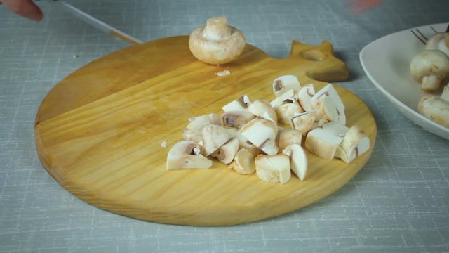 The girl shef in the kitchen sliced mushrooms clean the mushrooms. Cutting on a wooden board.