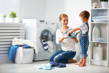 family mother and child girl  in laundry room near washing machi - obrazy, fototapety, plakaty