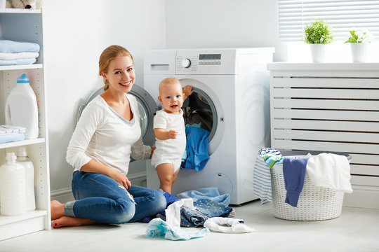 mother housewife with baby engaged in laundry fold clothes into