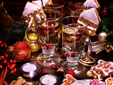 Four glasses of hot wine for whole family standing on wooden table. Christmas drinks decorated with Christmas cookies. Candles and Christmas balls in still life.