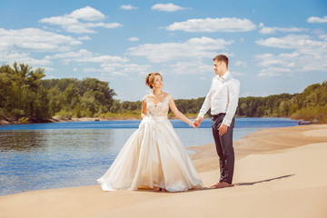 Fototapeta na wymiar Beautiful wedding couple is walking along beach at honeymoon