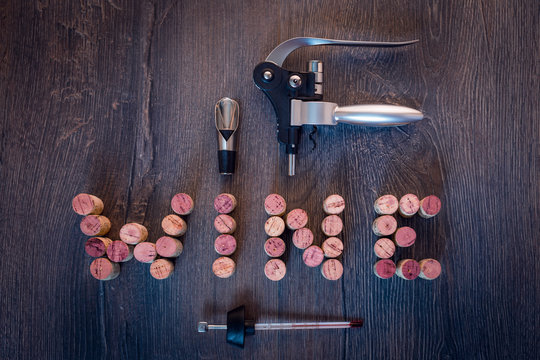Wine word out of corks with wine accessories on wooden background