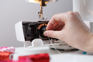 Girl inserts bobbin in sewing-machine
