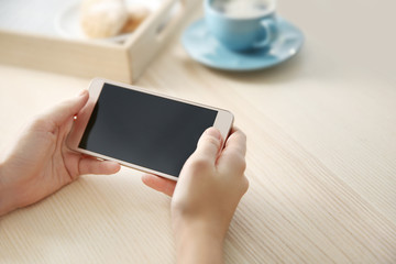 Woman with modern cellphone at table